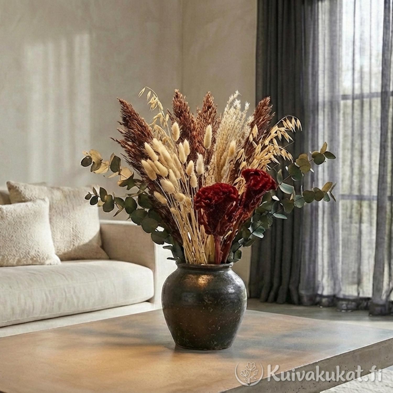 Tyylikäs kuivakukka-asetelma tummassa maljakossa betonipöydällä; mukana ruskeaa Kiinanmiskanttia, kanarianhelpeä ja eukalyptusta.