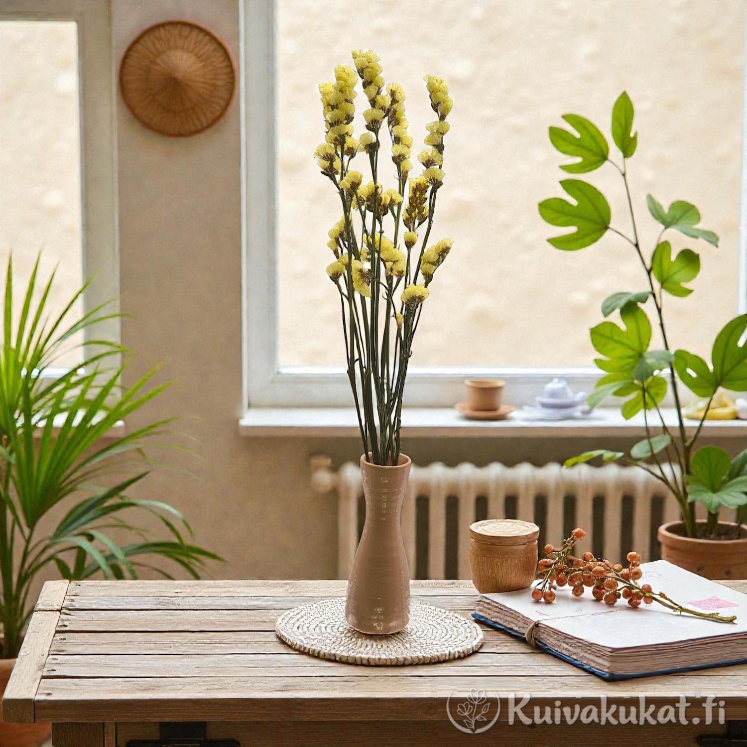 5 oksan kimppu keltaisia Ikiviuhko-kukkia (Limonium sinuatum) maljakossa puisella pöydällä.